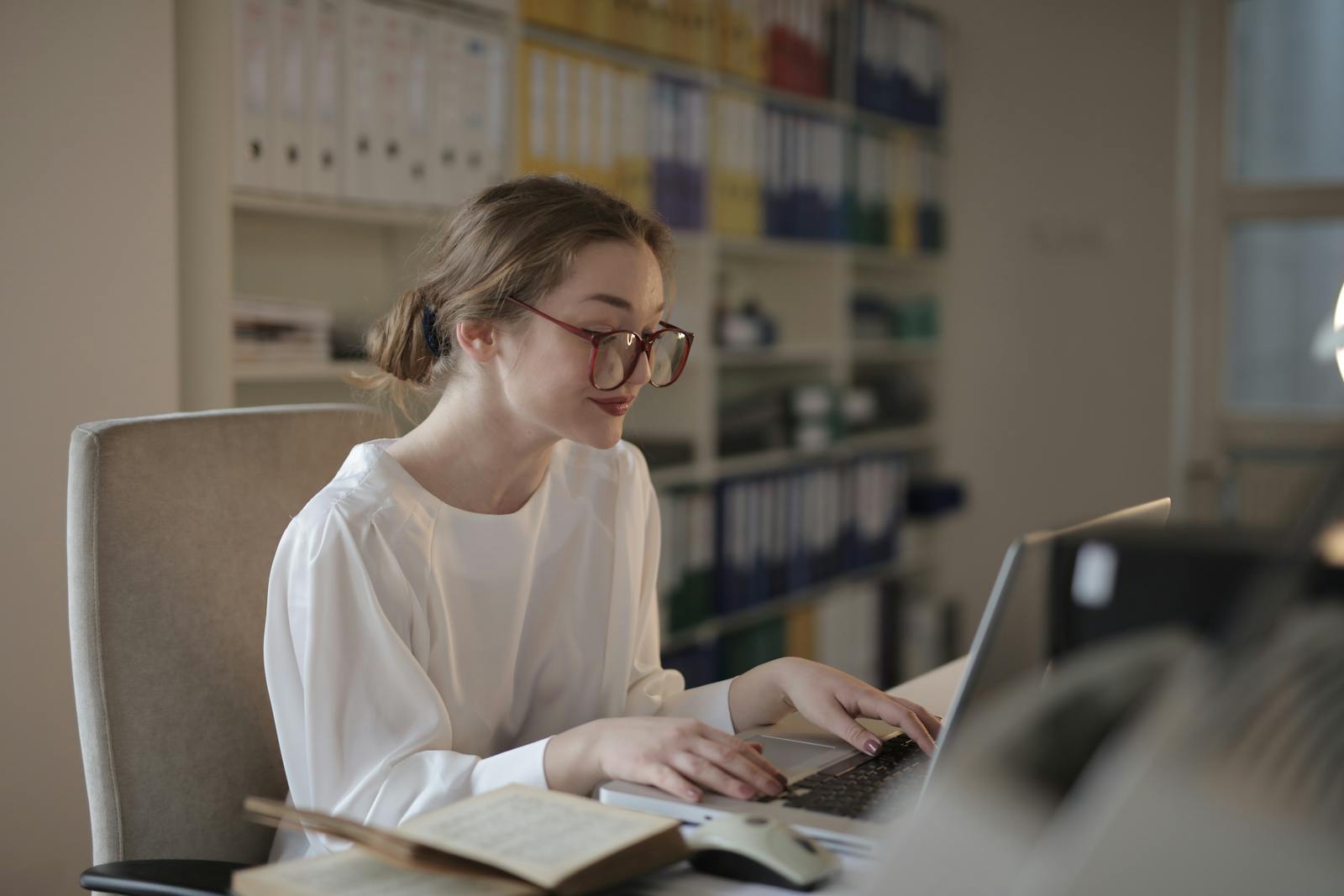 Adult working at a laptop wearing glasses